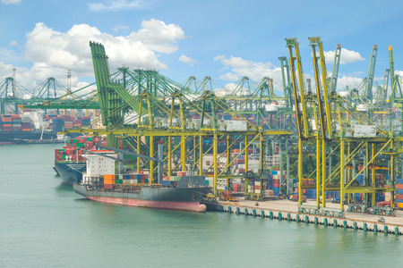 Industrial Container Cargo freight ship with working crane bridge in shipyard at dusk for Logistic...