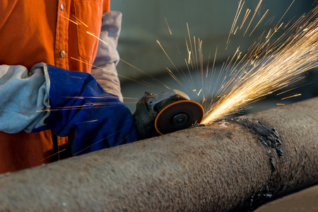 Worker cutting metal with grinder. Sparks while grinding ironの写真素材