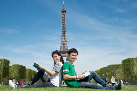 Asian couple student reading book together at outdoors park near Eiffel Tower in Paris, France. Abroad study in Paris, France.の写真素材