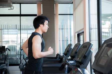 Asian young man running on treadmill in gym. Health and sport concept.の写真素材