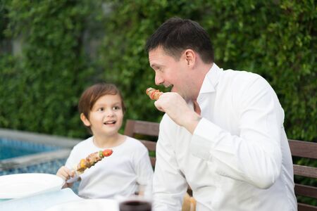 Father with little bcute boy eating barbecue in family lunch time at home.の写真素材