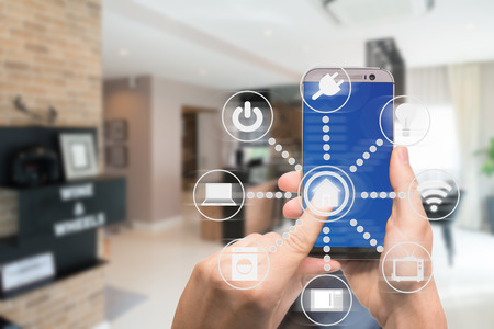 Smart home automation app on mobile with home interior in background. Internet of things concept at home. Smart technology 4.0の写真素材