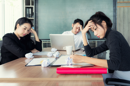 Group of unhappy Asian business people in casual suit sitting in business meeting room and looking strain.の写真素材