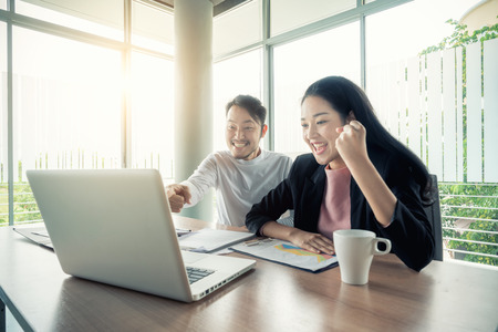 Asian couple business people with casual suit working with happy action in office Business people concept.の写真素材