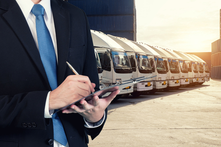 Businessman is booking with blurred cargo , transportation port and world map. Transportation logistic business concept.の写真素材