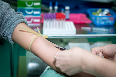Laboratory with nurse taking a blood sample from patient, in background samples blood .の写真素材