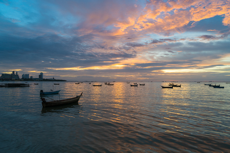 Many Thai fishing boat mooring in sea near Pattaya, Thailand at sunset.の写真素材