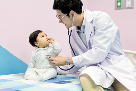 Asian doctor man examining a little boy by stethoscope in hospital. Medicine and health care concept.

の写真素材