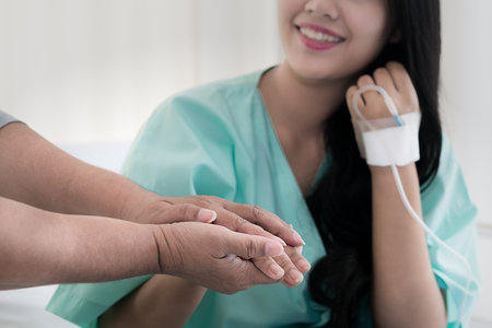 Mother hands holding her daughter patient hand sitting at the desk for encouragement, empathy, cheering and support while medical examination. Good news lessening, trust and ethics conceptの写真素材