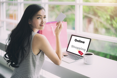Shopping Asian woman showing credit card for shopping online. Asian woman looking shop online for shopping in tablet.の写真素材