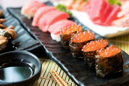 Sushi with chopsticks and soy sauce. Sushi roll japanese food in restaurant. Salmon roe Sushi set with salmon, vegetables, flying fish roe and caviar closeup. Japan restaurant menuの写真素材