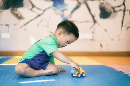 Asian kid boy toddler playing with toy car indoors home.の写真素材