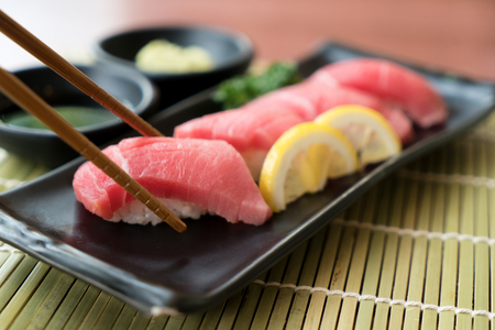 Otoro tuna sushi on black plate along with Japanese sauce and green leaf decoration, Japanese food, close up at sushi .の写真素材