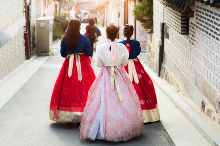 Back of three woman wearing hanbok walking through the traditional style houses of Bukchon Hanok Village in Seoul, South Korea.のeditorial素材