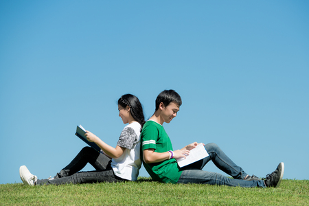 Asian couple student reading book together at outdoors park in universityの写真素材