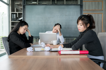 Group of unhappy Asian business people in casual suit sitting in business meeting room and looking strain.の写真素材