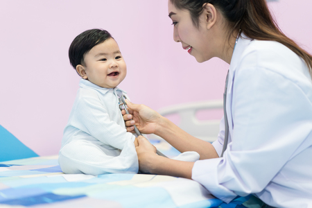 Asian doctor woman examining a little boy by stethoscope in hospital. Medicine and health care concept.の写真素材