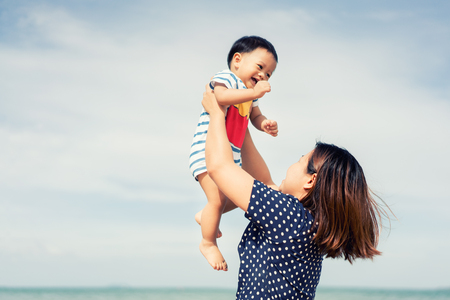 Portrait of Asian family happy loving mother and her baby playing fun at beach. Summer, Vacation, Travel and Holiday famil concept.の写真素材