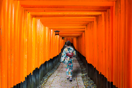 Geishas among red wooden Tori Gate at Fushimi Inari Shrine in Kyoto, Japan. Woman wearing traditional japanese kimono in Kyoto, Japan.のeditorial素材