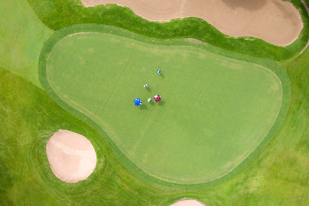Aerial view of players on a green golf course. Golfer playing on putting green on a summer day.のeditorial素材