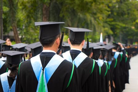 Rear view of group of university graduates in black gowns lines up for degree in university graduation ceremony. Concept education congratulation, student, successful to study.の写真素材