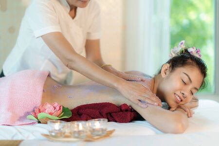 Asian young woman lying on bed and smile having massage and spa salon with spa salt in background  Beauty treatment concept. She is very happy to massage and spa.の写真素材