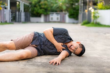 Asian man having heart attack or heart failure at street in home village.  Chest pained seem to be he will get heart attack from disease. Healthcare Medical Concept.の写真素材