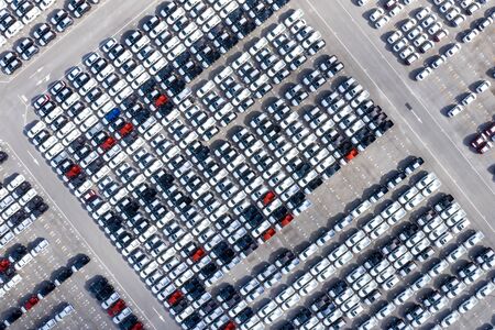 Aerial top view new cars lined up in the port for import export business logistic and transportation by ship in the open sea. New car from the factory parked at the portの写真素材