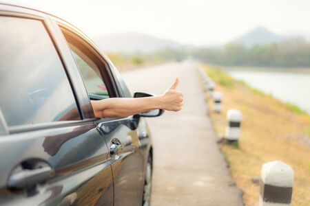 Hand of man traveler with thumbs up from car form the asphalt road go to travel with beautiful...