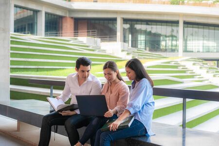 Three Asian students are discussing about exam preparation, presentation, study, study for test preparation with laptop in University. Education, Learning, Student, Campus, University, Lifestyle concept.の写真素材