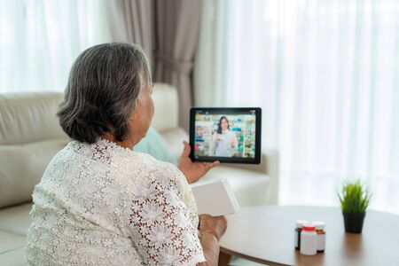Asian senior woman using video conference, make online consultation with pharmacy consulting about illness and medication via video call. Telehealth, Telemedicine and online hospital.の写真素材