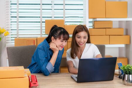 Two Asian teenager owner business woman work from home on the table for online shopping, checking order for delivery mail shipping with office equipment, entrepreneur lifestyle conceptの写真素材