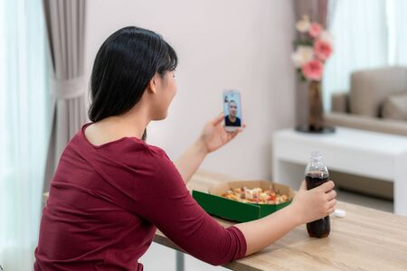 Asian woman virtual happy hour meeting dinner and eating pizza food online together with her boyfriend in video conference with digital tablet for a online meeting in video call for social distancing
の写真素材