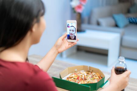 Asian woman virtual happy hour meeting dinner and eating pizza food online together with her boyfriend in video conference with digital tablet for a online meeting in video call for social distancing
の写真素材