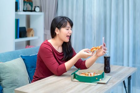 Asian woman virtual happy hour meeting dinner and eating pizza food online together with her boyfriend in video conference with digital tablet for a online meeting in video call for social distancing
の写真素材
