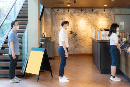 Three Asian people wearing mask standing distance of 6 feet from other people keep distance protect...