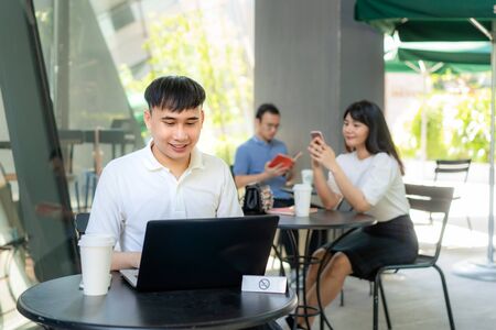 Asian young man and woman sitting one person per one table for distance of 6 feet distance protect from COVID-19 viruses for social distancing for infection risk at coffee cafe.の写真素材