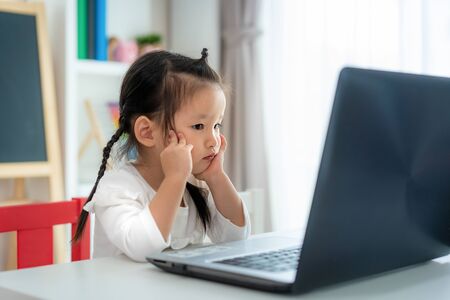 Asian kindergarten school girl video conference e-learning with teacher on laptop in living room at home. Homeschooling and distance learning ,online ,education protect from COVID-19 virus.の写真素材
