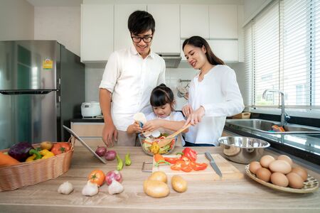 Asian family with father, mother and daughters preparing and cooking salad in the kitchen at home. Family life love relationship, or home fun leisure activity concept
の写真素材