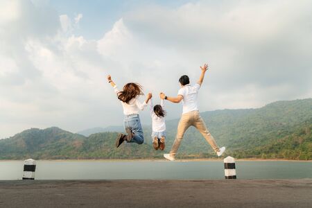Happy Asian family with father, mother and daughter jumping in road with lake and mountain view in background while vacation together in holiday. Happy family time.
の写真素材