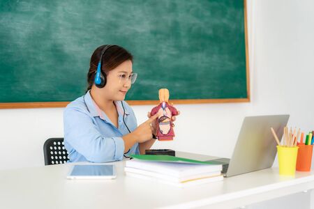 Asian woman teacher teaching physiology science via video conference e-learning in laptop with blackboard at classroom. Homeschooling and distance learning ,online ,education and internet.の写真素材