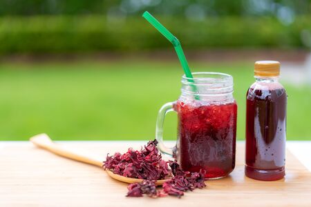 Cold beverage glass of roselle juice with colorful straw in wooden table Thai herb juice and refreshment cold drink.

の写真素材