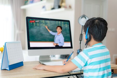 Asian  student boy video conference e-learning with teacher on computer in living room at home. E-learning ,online ,education and internet social distancing protect from COVID-19 virus.の写真素材