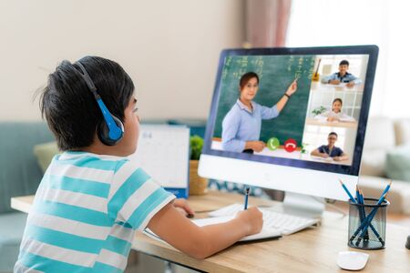 Asian boy student video conference e-learning with teacher and classmates on computer in living room at home. Homeschooling and distance learning ,online ,education and internet.の写真素材