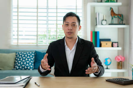Mixes race Businessman talk with his client by video call communication remote location use modern meeting online in living room at home for social distancing.の写真素材