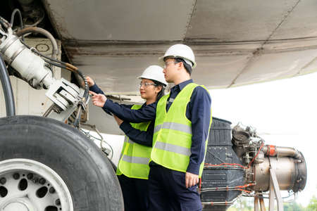 Asian man and woman engineer maintenance airplane team repairs, fixes, modernization and renovation in front airplane from  in airport.の写真素材