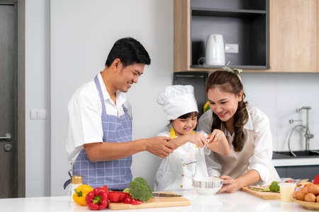 Young Asian love family are preparing food dinner on table in the kitchen which father and mother...