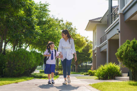 Happy Asian mother and daughter primary school student walking to school in the morning school routine for day in the life getting ready for school.の写真素材