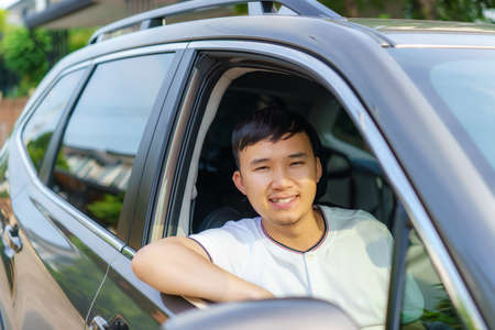 Asian happy young handsome man driving a car in front seat with smile prepare to journey with his car.の写真素材