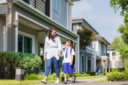 Happy Asian mother and daughter primary school student walking to school in the morning school routine for day in the life getting ready for school.の写真素材
